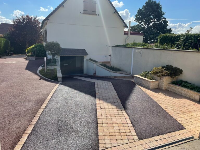 Réalisations de terrassement dans le Calvados : allée en enrobé noir et pavés devant un garage, chantier STAPV