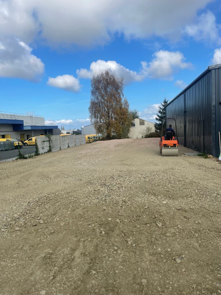 Réalisations de terrassement dans le Calvados : compactage au rouleau d'une plateforme de parking avant enrobé, chantier STAPV