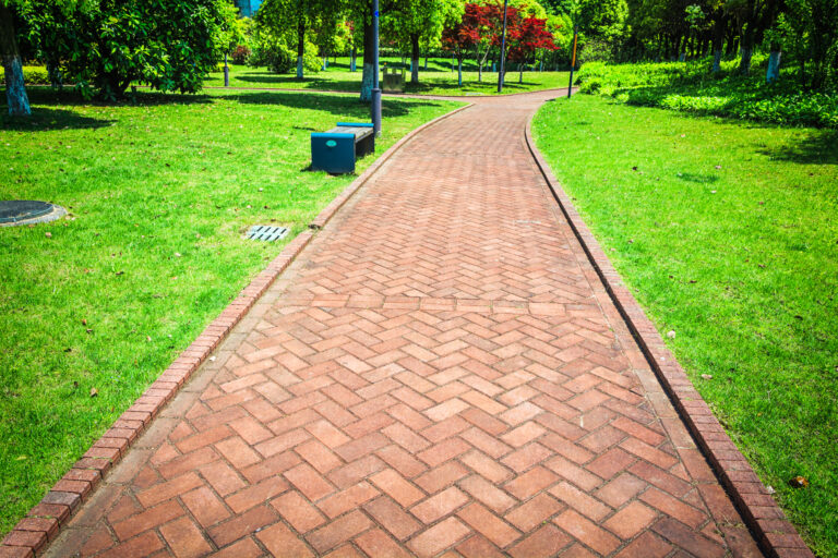 Allée en pavés posés en chevrons, bordée de pelouse