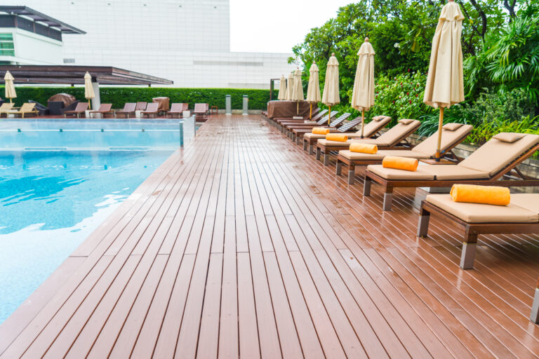 Terrasse en bois au bord d'une piscine avec transats