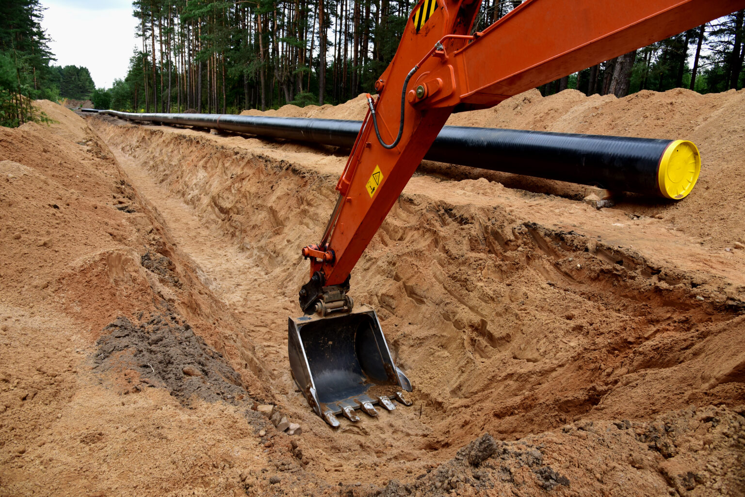 Travaux d'assainissement dans le Calvados : tranchée ouverte avec canalisation posée, pelle en action